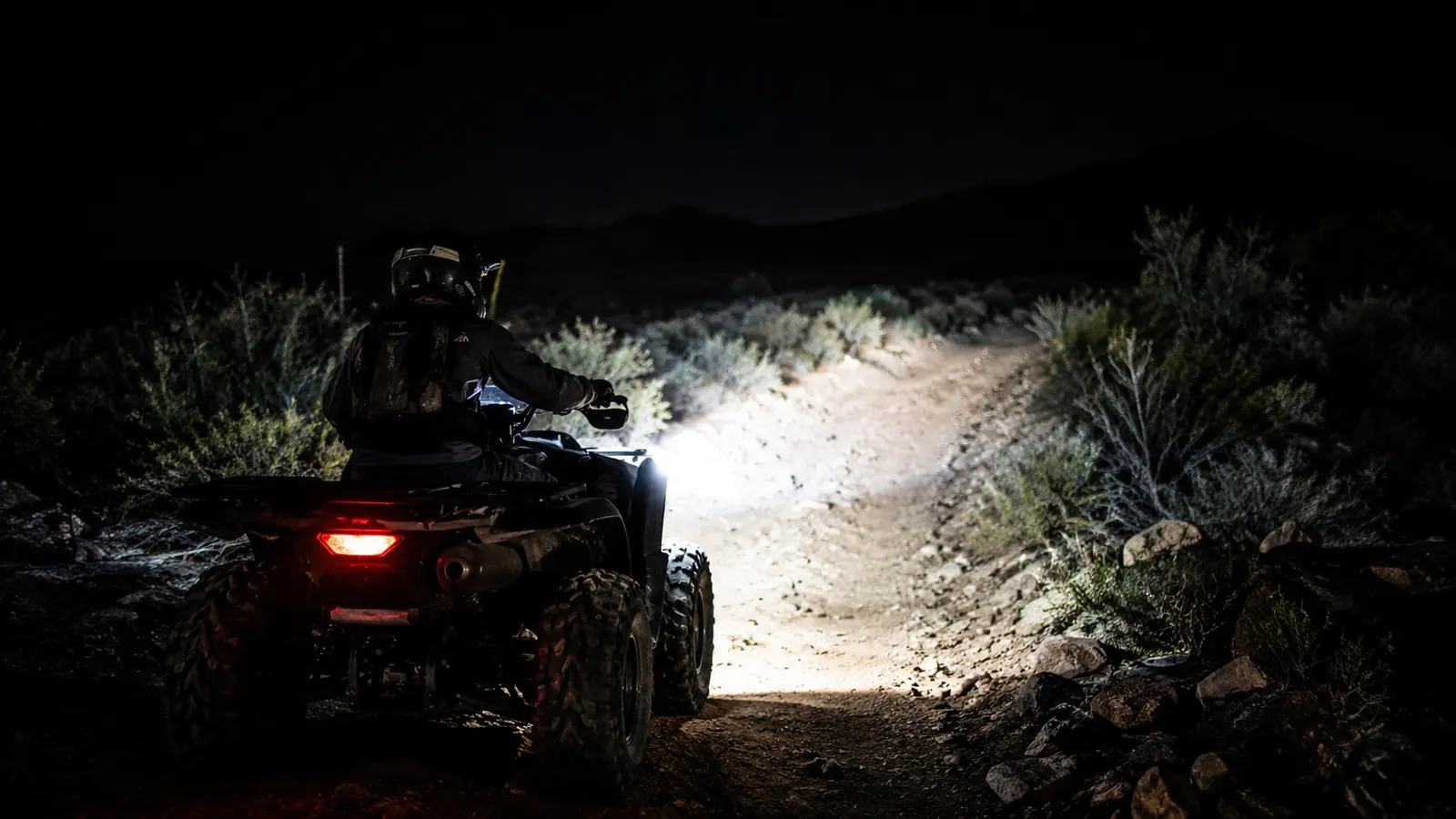 Rider on an ATV at night on a desert wash, LED pods lighting the trail ahead