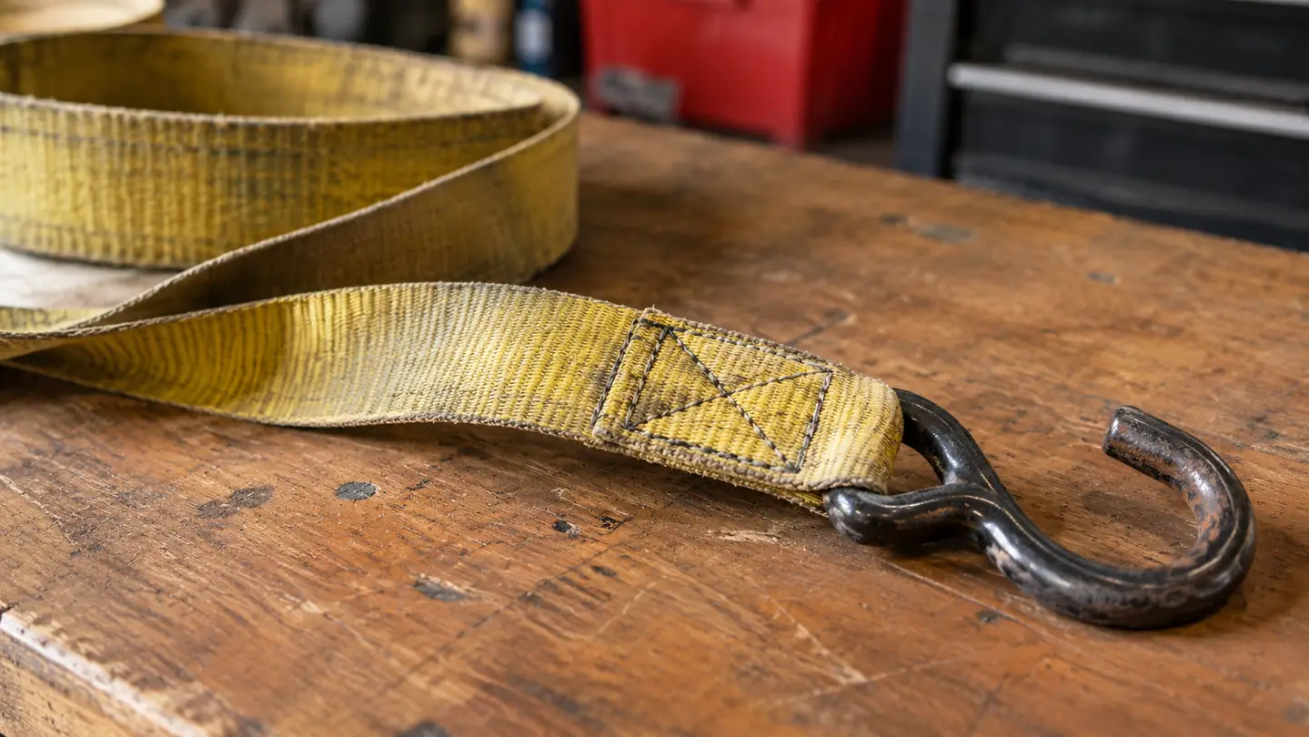 Close view of faded strap webbing and box stitching being inspected on a workbench